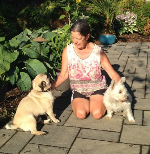 Jeannette kneeled on a garden path with Cloe (Terrier mix) and Rideau (pug). 